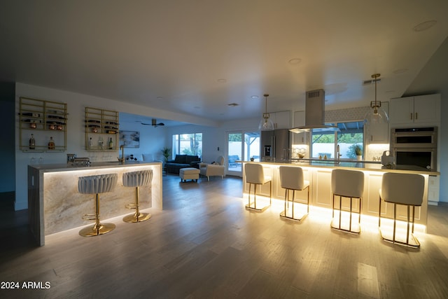 kitchen featuring a breakfast bar, white cabinetry, plenty of natural light, and light hardwood / wood-style flooring