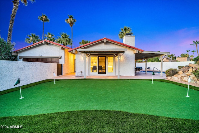 back house at dusk with a fenced in pool and a patio area