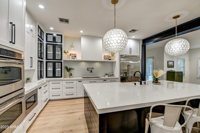 22406 S 173rd Way, Gilbert, AZ 85298 - kitchen with stainless steel appliances, light wood finished floors, white cabinetry, a breakfast bar area, and hanging light fixtures