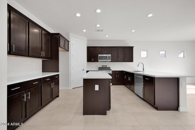 kitchen with light countertops, appliances with stainless steel finishes, a sink, a kitchen island, and a peninsula