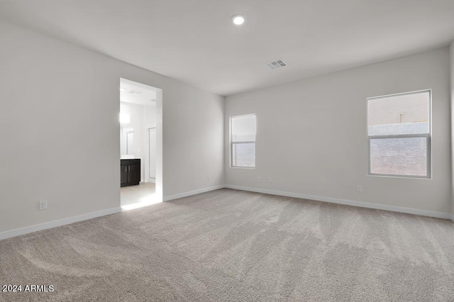 empty room featuring light carpet, visible vents, and baseboards