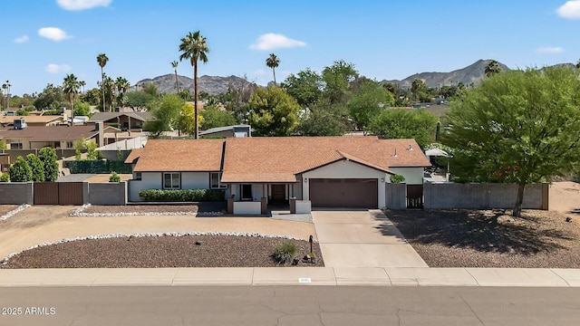 5101 E Paradise Dr, Scottsdale, AZ 85254 - ranch-style home with an attached garage, concrete driveway, a mountain view, a residential view, and a gate