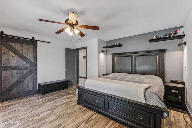 5101 E Paradise Dr, Scottsdale, AZ 85254 - bedroom with light wood-style floors, a barn door, and a ceiling fan