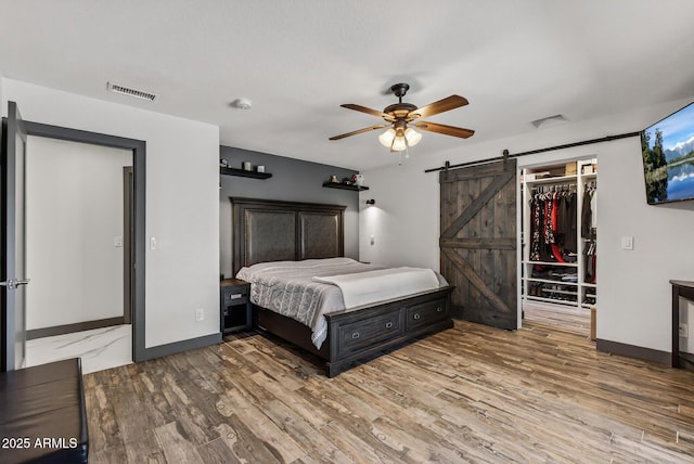 5101 E Paradise Dr, Scottsdale, AZ 85254 - bedroom featuring a barn door, wood finished floors, a walk in closet, and a closet