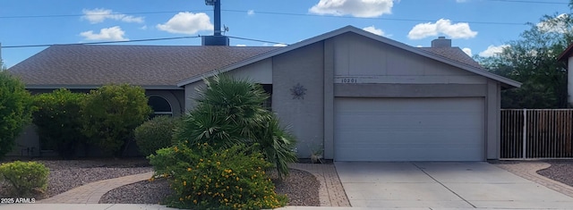 view of front of house featuring fence, a chimney, a shingled roof, concrete driveway, and an attached garage