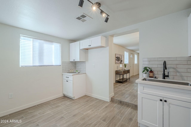 kitchen with white cabinets, sink, backsplash, and light hardwood / wood-style flooring