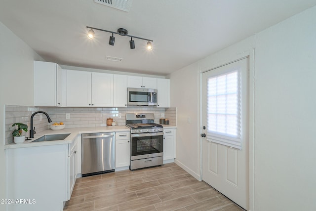 kitchen with sink, stainless steel appliances, light hardwood / wood-style flooring, backsplash, and white cabinets