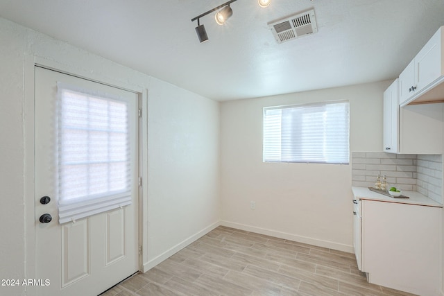 unfurnished dining area featuring light wood-type flooring and rail lighting