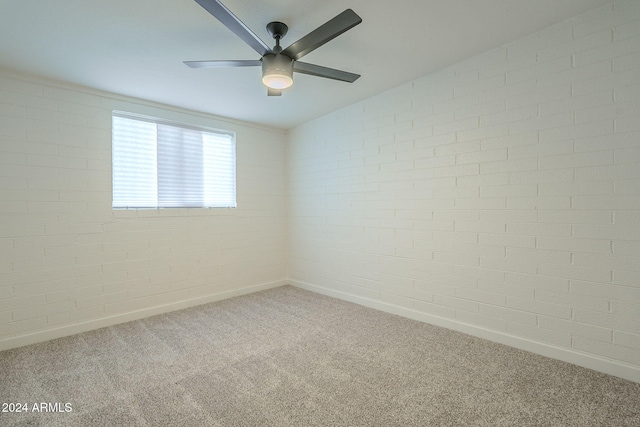 spare room featuring ceiling fan, carpet, and brick wall