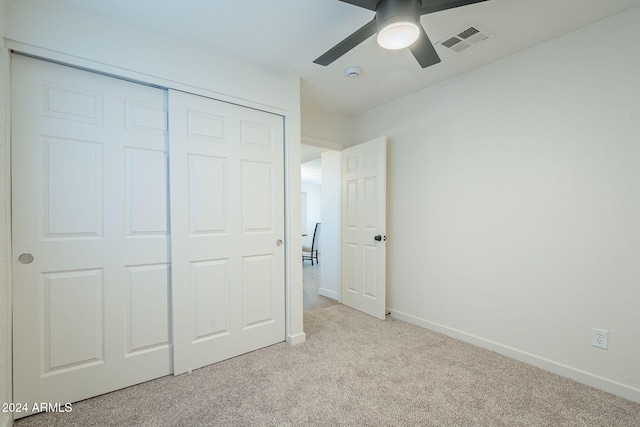 unfurnished bedroom featuring ceiling fan, light colored carpet, and a closet