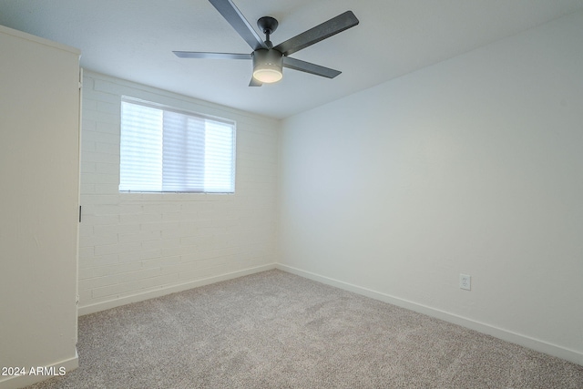 unfurnished room featuring carpet floors, ceiling fan, and brick wall