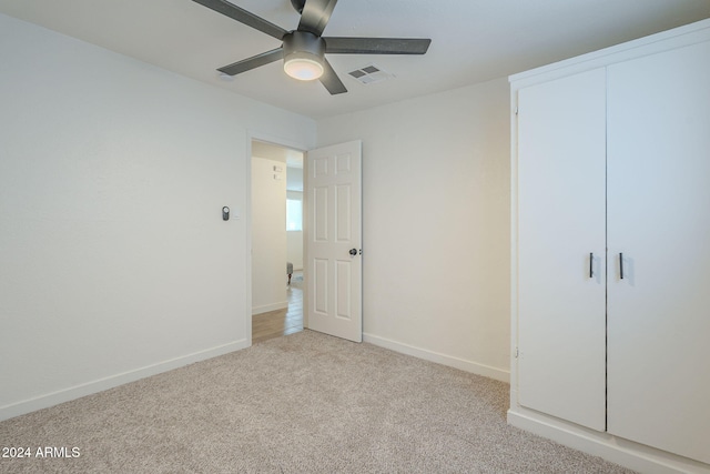 unfurnished bedroom featuring ceiling fan, a closet, and light colored carpet