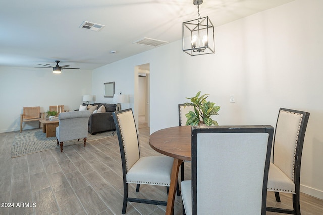 dining area featuring hardwood / wood-style floors and ceiling fan with notable chandelier