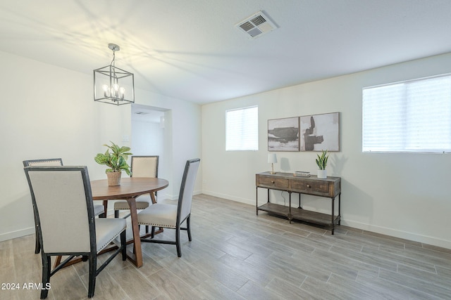 dining room with light hardwood / wood-style floors and an inviting chandelier