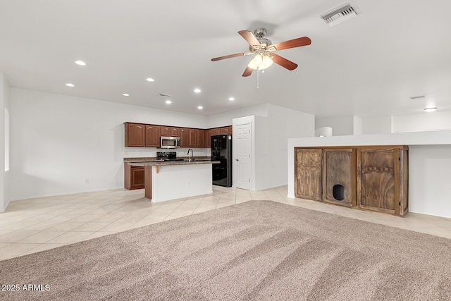 kitchen with ceiling fan, sink, a kitchen island with sink, light tile patterned flooring, and black appliances