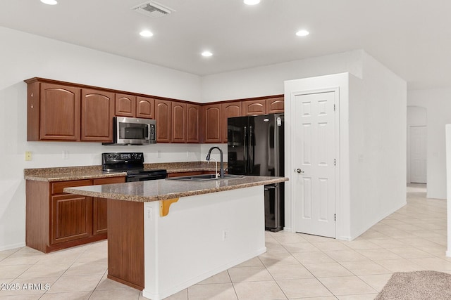 kitchen featuring a kitchen breakfast bar, sink, black appliances, an island with sink, and light tile patterned flooring