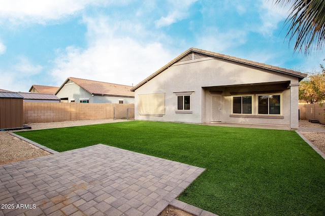 back of property with a lawn, a storage unit, and a patio area