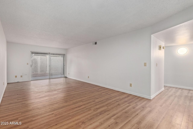 unfurnished room featuring light wood-type flooring and a textured ceiling