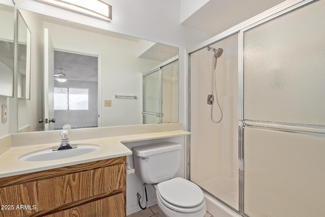 bathroom with a textured ceiling, a shower with door, vanity, toilet, and ceiling fan