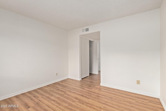 empty room with a textured ceiling and light wood-type flooring