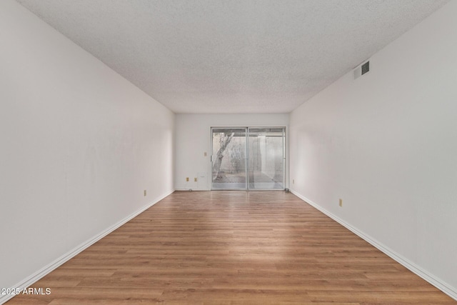 spare room featuring light hardwood / wood-style flooring and a textured ceiling