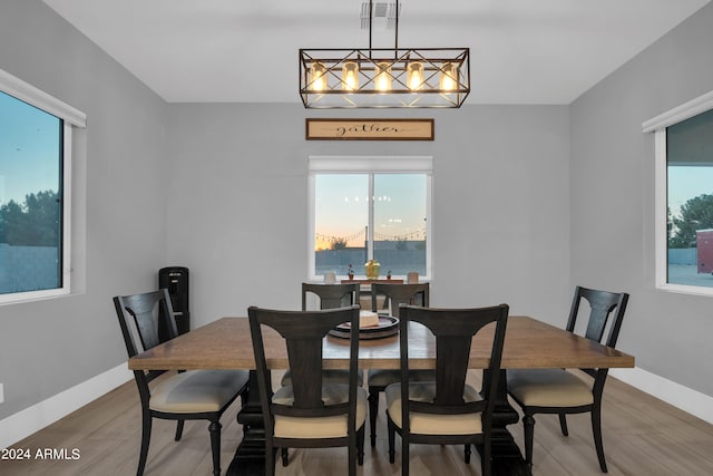 dining space with an inviting chandelier, baseboards, visible vents, and wood finished floors