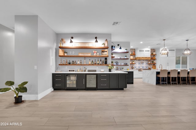 bar with wine cooler, bar area, visible vents, light wood-style floors, and pendant lighting