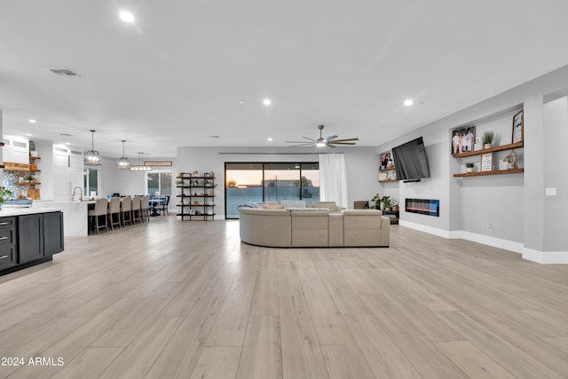 unfurnished living room with recessed lighting, a ceiling fan, visible vents, light wood-style floors, and a glass covered fireplace