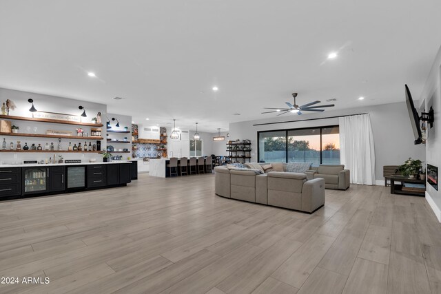 living area featuring light wood finished floors, ceiling fan, a dry bar, and recessed lighting