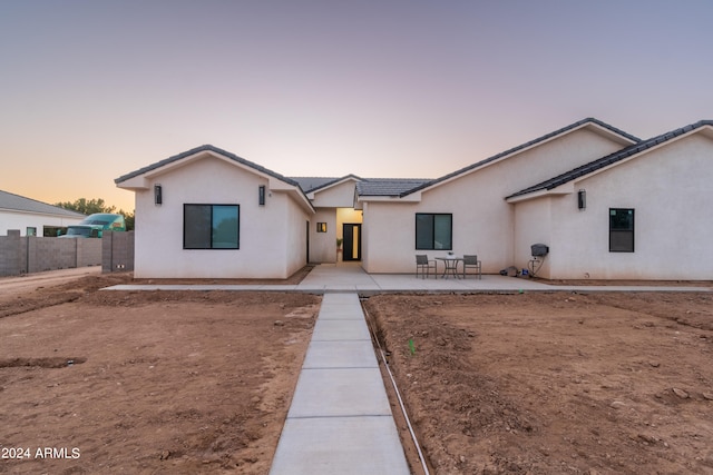 view of front of house featuring a patio area, fence, and stucco siding