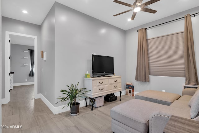 living area with ceiling fan, light wood finished floors, and baseboards