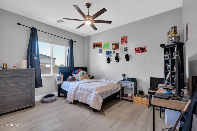 bedroom with ceiling fan, light wood-type flooring, visible vents, and baseboards