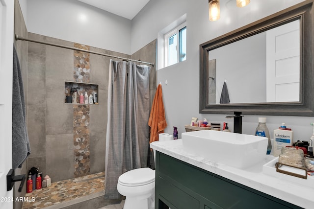 bathroom featuring toilet, a tile shower, and vanity