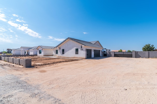 exterior space featuring driveway, a garage, fence, and stucco siding