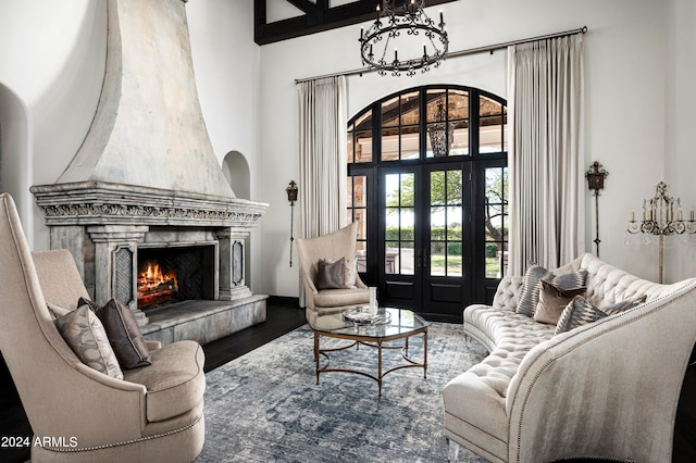 living room featuring a premium fireplace, a notable chandelier, hardwood / wood-style floors, and a towering ceiling