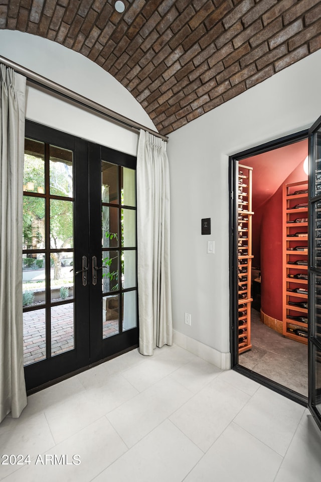 unfurnished room with lofted ceiling, brick ceiling, and french doors