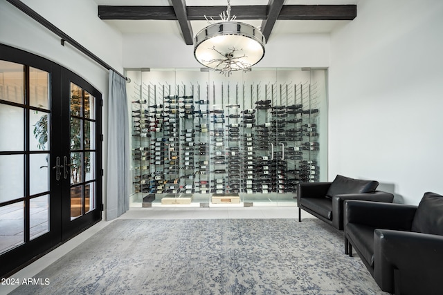 wine cellar with french doors, beamed ceiling, coffered ceiling, and a notable chandelier