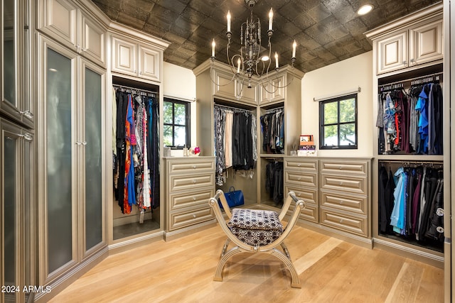 walk in closet featuring light hardwood / wood-style flooring and a chandelier