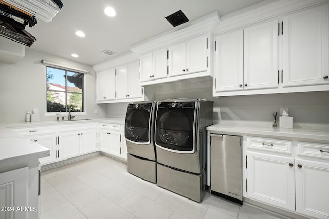 laundry area featuring washer and clothes dryer, light tile patterned floors, cabinets, and sink