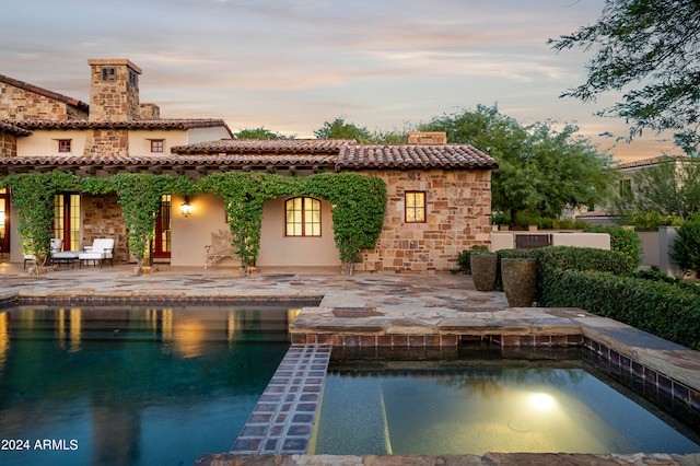 pool at dusk featuring a patio area