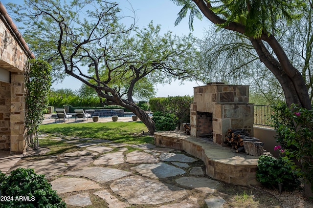 view of patio / terrace with an outdoor stone fireplace and a pool