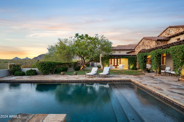 pool at dusk with a patio area