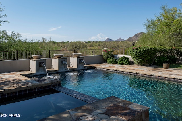 view of swimming pool with pool water feature and a mountain view