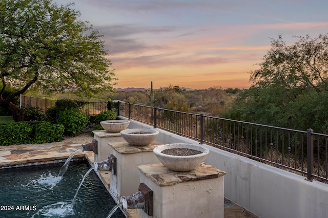 patio terrace at dusk featuring pool water feature