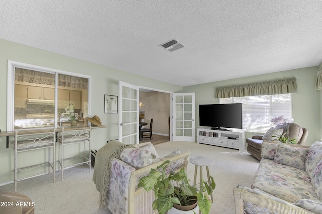 living room with french doors, a textured ceiling, and light carpet