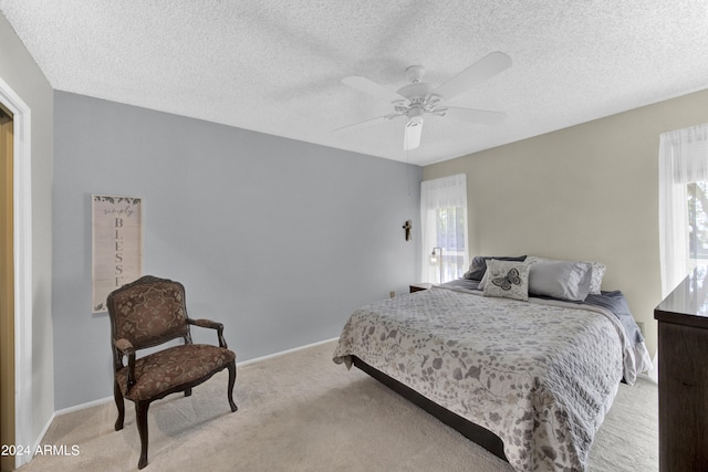 bedroom featuring light carpet, ceiling fan, and a textured ceiling