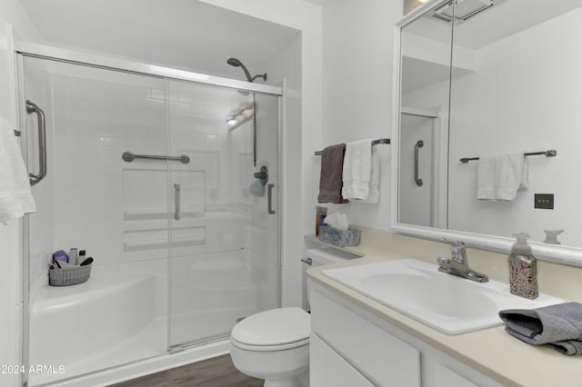 bathroom with hardwood / wood-style flooring, vanity, walk in shower, and toilet