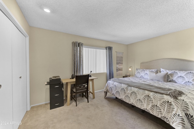 bedroom featuring a closet, a textured ceiling, and light carpet