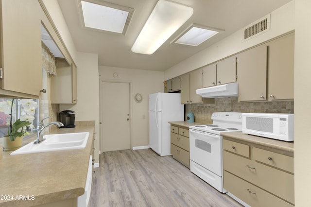 kitchen with white appliances, sink, light hardwood / wood-style flooring, a skylight, and backsplash