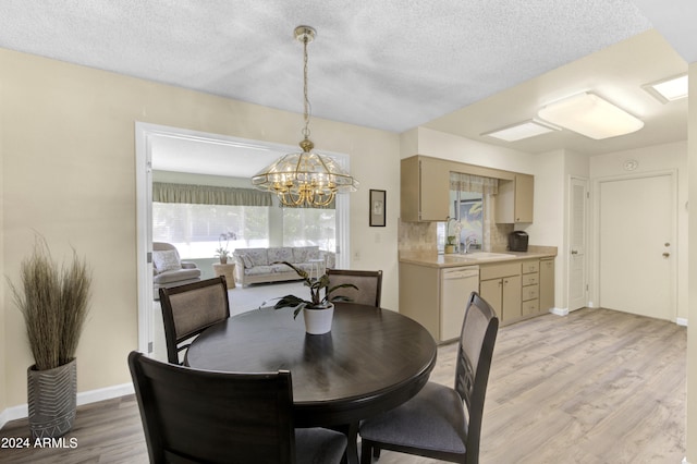 dining room with an inviting chandelier, light hardwood / wood-style floors, sink, and a textured ceiling